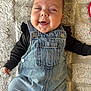 baby, infant, denim_overalls, black_shirt, smiling, happy, face, cheeks, lying_down, blanket, texture, clothing, cute, child, portrait, indoors, one_person, casual, joyful, small_hand