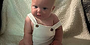 Hazelee is registered to the contest to win money with this photo: baby, infant, child, fluffy_blanket, white_overall, buttons, sitting, curly_hair, plush, soft_texture, indoor, cute, portrait, wide_eyes, skin, small_hands, small_feet, cozy, comfortable, looking