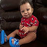 toddler, child, curly_hair, red_clothing, blue_sandals, smile, face, sitting, leather_couch, indoor, cute, happy, young_child, portrait, person, feet, legs, furniture, home, casual_clothing
