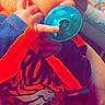 baby, sleeping, pacifier, hand_gesture, orange_clothing, navy_clothing, denver_broncos_logo, infant, person, holding, closeup, indoor, blurred_background, cute, newborn, child, toddler, soft_lighting, resting, cozy
