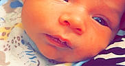 Keano joined the competition — help win amazing prizes! baby, newborn, infant, face, closeup, bib, animal_print, fabric, pattern, skin, eyes, mouth, head, person, resting, soft_lighting, cute, child, portrait, young