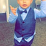 Joseph is registered to the contest to win money with this photo: child, toddler, boy, suit, bow_tie, blue_shirt, vest, pants, shoes, carpet, indoor, posing, standing, expression, hands, face, eyes, hair, chair, door