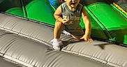 Lylah is registered to the contest to win money with this photo: child, toddler, smiling, playground, indoor, inflatable, bouncy_castle, play_mat, minnie_mouse, cartoon, colorful, portrait, sitting, jumping, sneakers, hair_bows, casual_clothing, background_child, family_fun, recreation