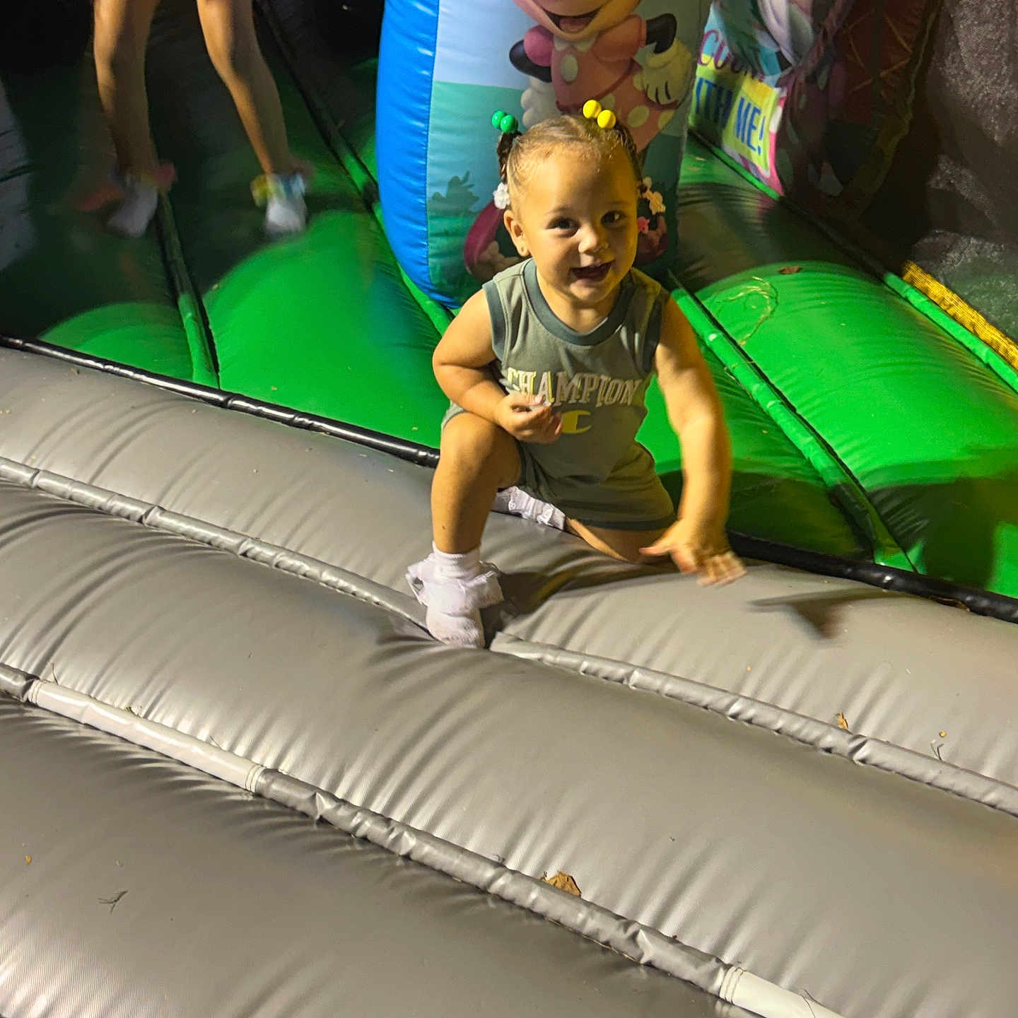 Lylah is registered to the contest to win money with this photo: child, toddler, smiling, playground, indoor, inflatable, bouncy_castle, play_mat, minnie_mouse, cartoon, colorful, portrait, sitting, jumping, sneakers, hair_bows, casual_clothing, background_child, family_fun, recreation