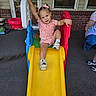 Lylah joined the competition — help win amazing prizes! toddler, child, slide, playground, outdoor, smiling, happy, portrait, pink_clothing, hair_bows, sneakers, play_equipment, backyard, patio, brick_wall, house, window, adult, summer, recreation