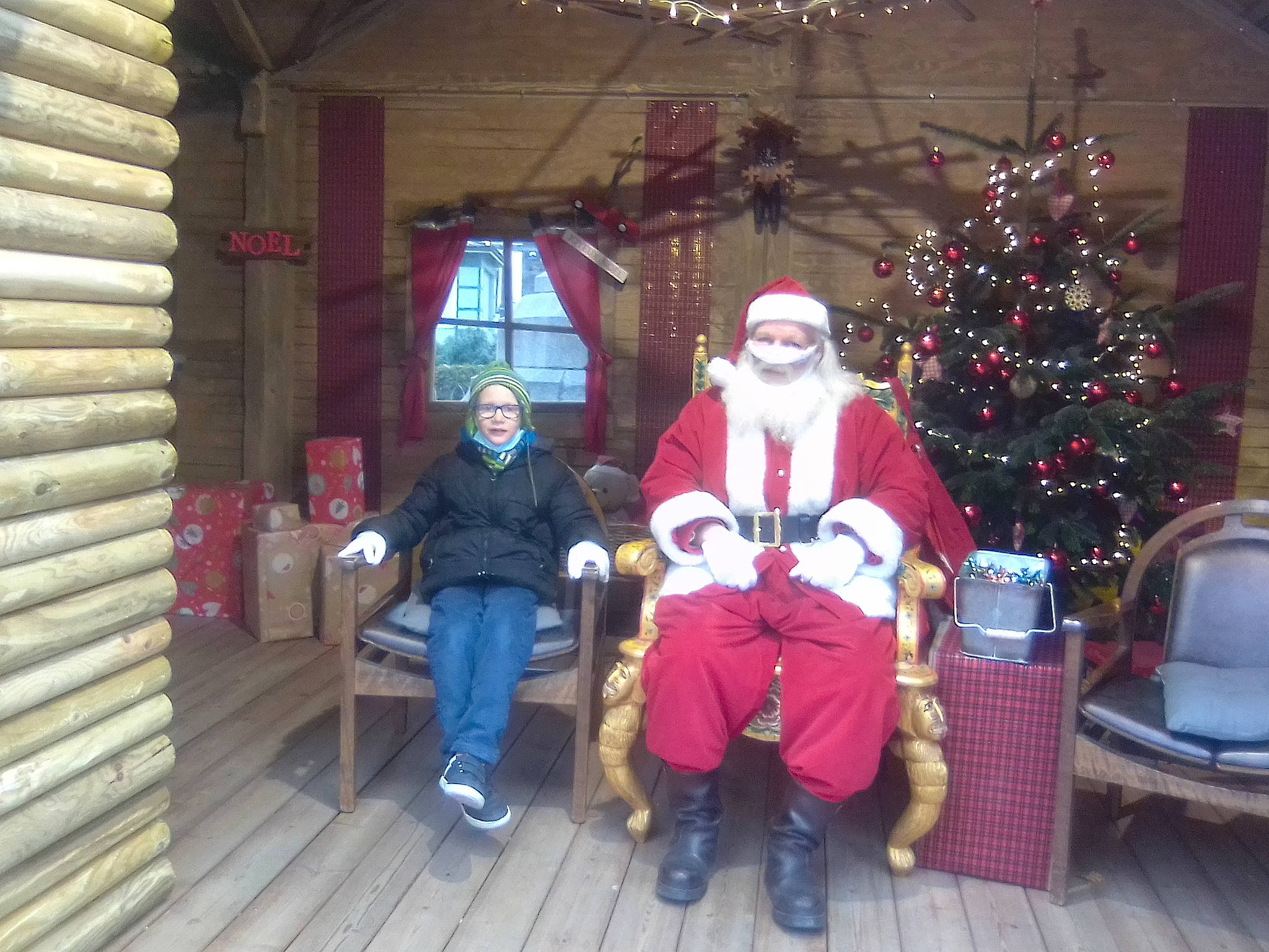 Leo participe au concours pour gagner de l'argent avec cette photo : beard, christmas, christmas_decoration, christmas_ornament, christmas_tree, event, fun, hat, headwear, holiday, holiday_ornament, lap, leisure, ornament, person, santa_claus, sitting, smile, tree, window