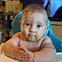 baby, high_chair, food, face, hands, messy, indoor, television, person, child, curious, blue_chair, expression, home, kitchen, light, skin, hair, cute, smudge