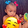 child, toddler, hair_bows, blue_bow, red_bow, couch, plush_couch, toy, sippy_cup, indoor, diaper, young_child, cute, seated, cute_expression, emoji_overlay, colorful, playtime, relaxed, home