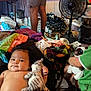baby, child, stuffed_animal, plush_toy, blanket, clothing, indoor, fan, person, toy, colorful, messy_room, floor, legs, diapers, water_bottle, fabric, couch, toddler, smile