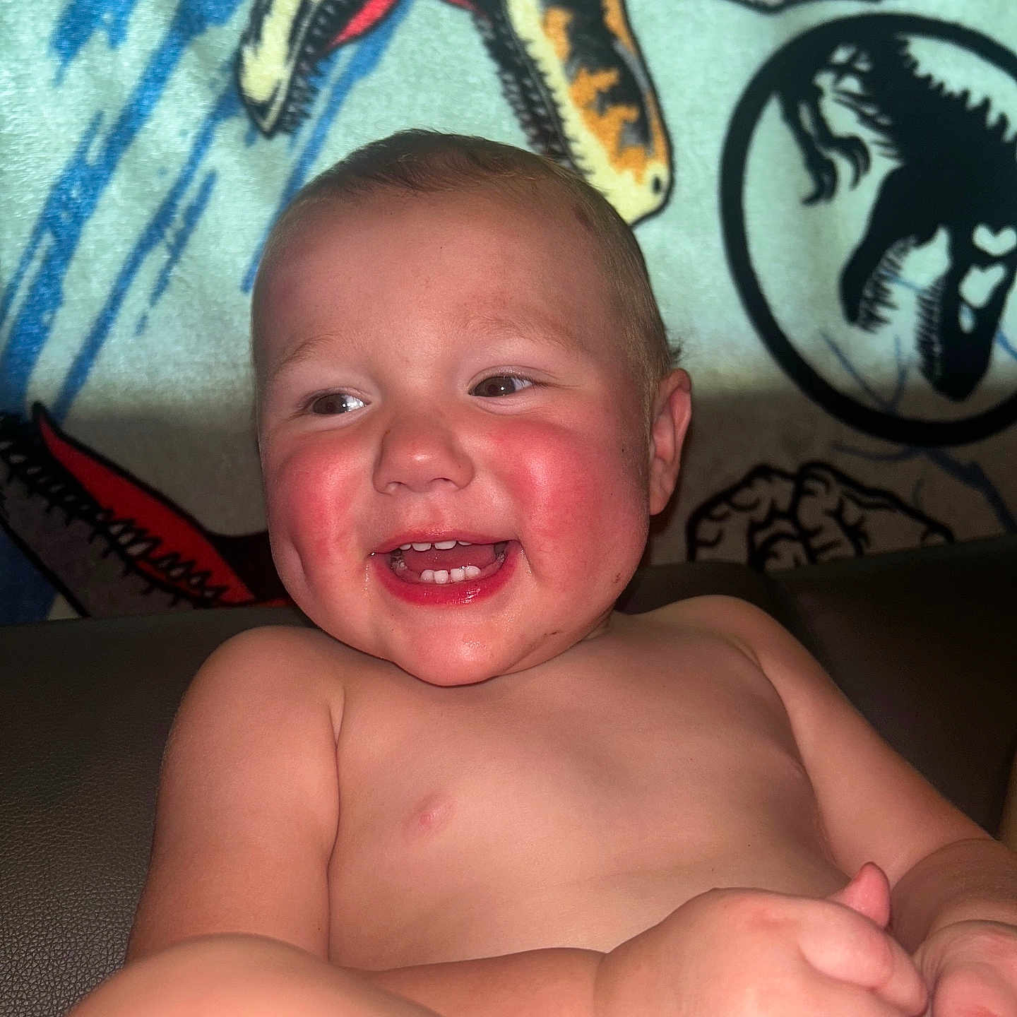 Keaton is registered to the contest to win money with this photo: baby, background, blanket, cheerful, child, couch, cute, dinosaur, happy, indoors, infant, laughing, person, portrait, rosy_cheeks, seated, shirtless, skin, smiling, young