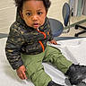 Kartier joined the competition — help win amazing prizes! toddler, child, curly_hair, camo_jacket, cargo_pants, black_boots, medical_exam_table, clinic_room, chair, curtain, floor, wall, person, sitting, looking, indoor, young_child, casual_clothing, expression, waiting
