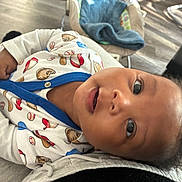 Luphiwe is registered to the contest to win money with this photo: baby, child, infant, onesie, baseball_theme, blue_trim, smiling, curious, face, eyes, hand, indoor, baby_rocker, blanket, floor, wood_floor, person, closeup, portrait, happy