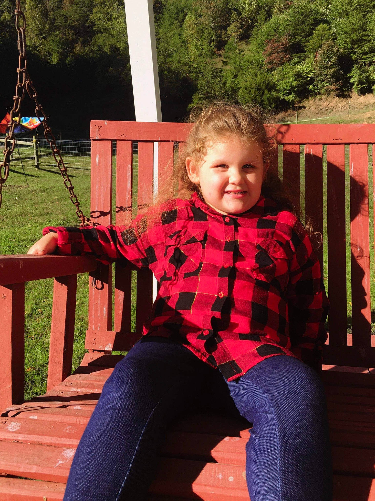 Destiny is registered to the contest to win money with this photo: backyard, child, jeans, joy, leaf, leisure, outdoor_play_equipment, people, person, pink, plant, play, playground, public_space, recreation, red, sitting, smile, swing, toddler