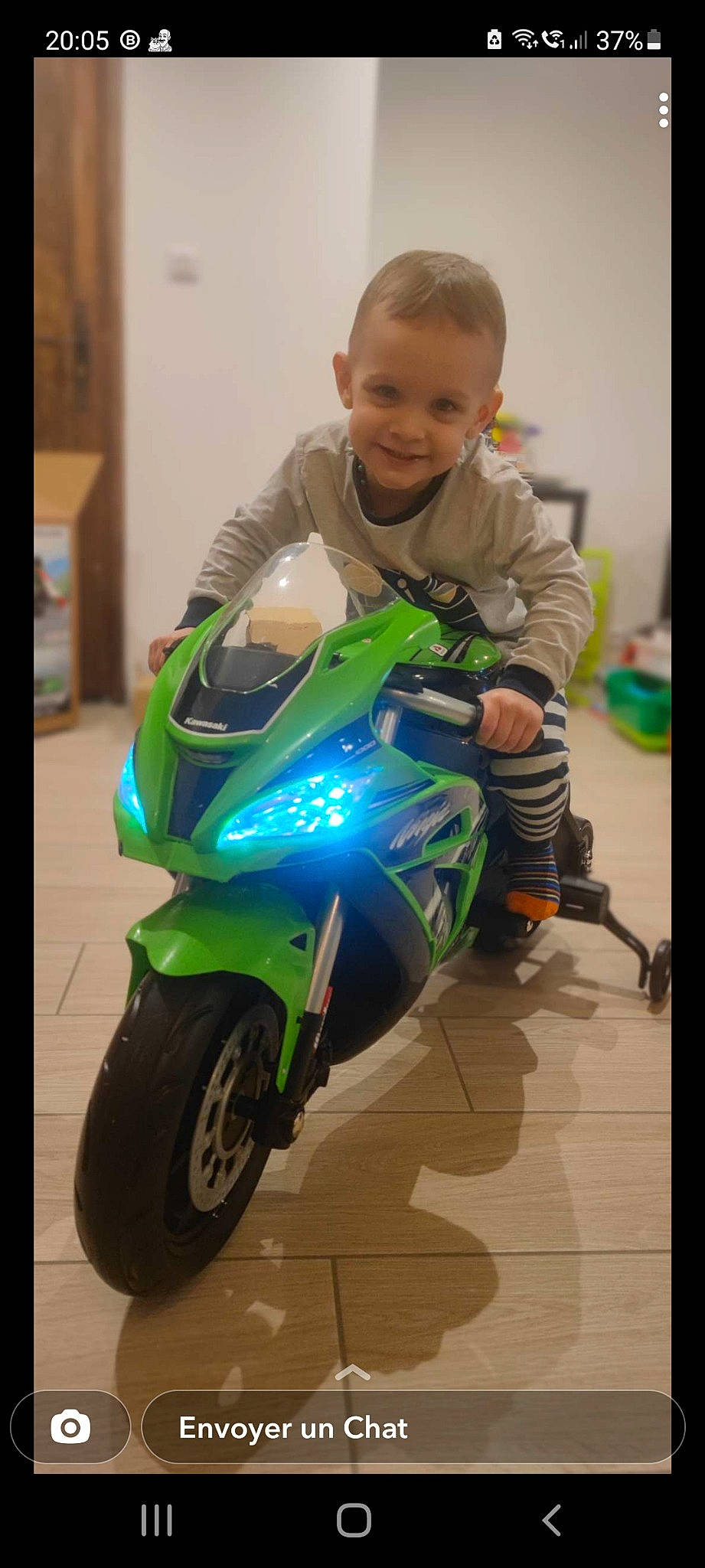 Hugo a rejoint le concours — aidez-le/la à gagner de superbes lots ! arm, automotive_design, automotive_exterior, automotive_lighting, automotive_tire, clothing, fender, flooring, headlamp, helmet, joy, motor_vehicle, motorcycle, person, personal_protective_equipment, rim, smile, tire, toddler, toy