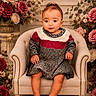 baby, child, portrait, sitting, armchair, dress, sweater, roses, flowers, floral_background, indoors, studio, decor, furniture, infant, barefoot, looking_at_camera, formal_portrait, patterned_clothing, cozy