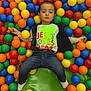 Tadeo is registered to the contest to win money with this photo: child, ball_pit, colorful_balls, toy_duck, play_area, jeans, tshirt, socks, indoor, netting, green_mat, casual_clothing, portrait, looking_at_camera, young_child, playtime, fun, multicolor, relaxed, kid