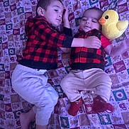 Tadeo is registered to the contest to win money with this photo: child, baby, toddler, plush_toy, duck, blanket, patterned, red_and_black, checkered, clothing, lying_down, hugging, cute, indoor, family, siblings, comfort, soft_toys, feet, playful