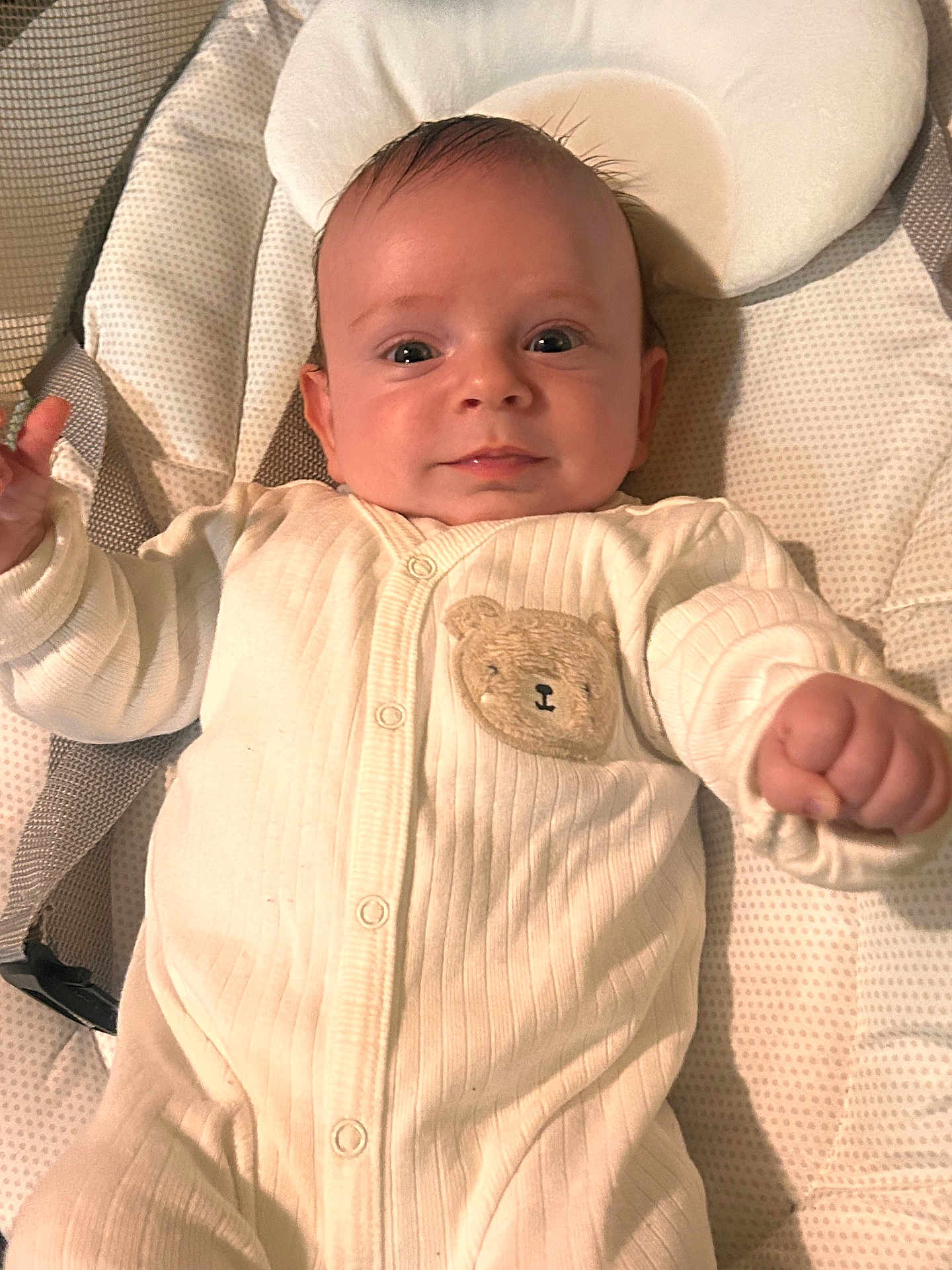 Siar is registered to the contest to win money with this photo: baby, infant, onesie, teddy_bear_patch, cushion, baby_seat, smiling, face, hand, cute, comfort, indoor, child, newborn, portrait, soft_lighting, white_clothing, happy, resting, young