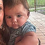 Colson is registered to the contest to win money with this photo: baby, child, person, portrait, outdoor, patio, hand, clothing, floral_pattern, diaper, fence, string_lights, arm, face, hair, watch, tile_floor, greenery, daylight, holding