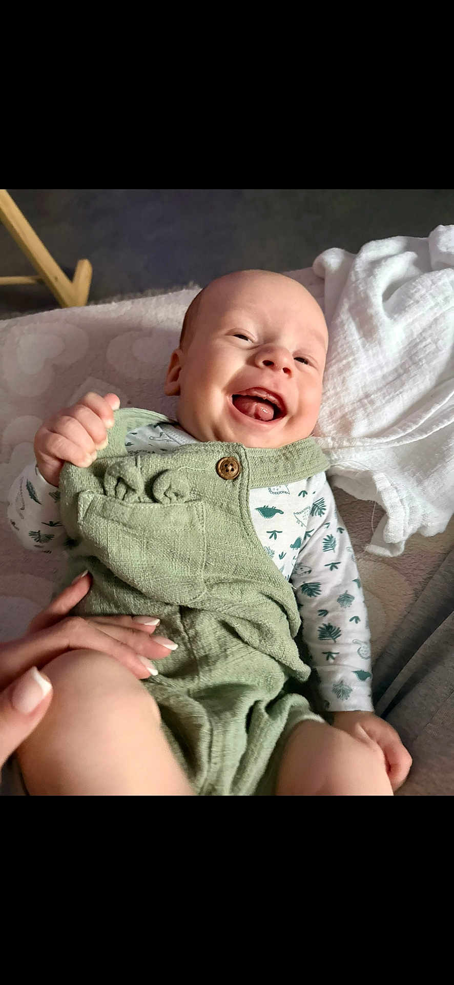 Liam participe au concours pour gagner de l'argent avec cette photo : baby, smiling, infant, green_overalls, white_blanket, hand, happy, clothing, lying_down, cute, child, indoors, soft_surface, portrait, skin, face, joy, expression, person, newborn