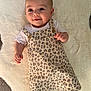 baby, infant, smiling, face, leopard_print, dress, white_shirt, buttons, soft_rug, lying_down, cute, child, apparel, happy, skin, head, eyes, hand, footwear, indoors