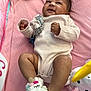 baby, infant, smiling, lying_down, pink_blanket, onesie, unicorn_slippers, plush_toy, soft_toys, indoors, cute, child, happy, cozy, small_hands, small_feet, looking_up, infant_clothing, baby_accessories, play_area