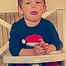 child, toddler, high_chair, tongue_out, playful, indoor, festive_clothing, santa_hat, cute, person, face, smiling, hands, table, chair, young_child, clothing, expression, portrait, home