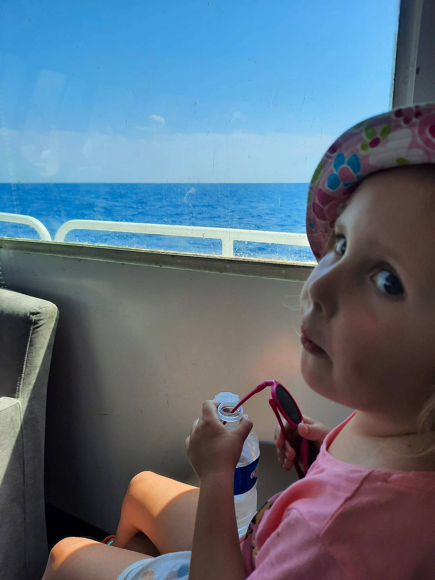 Taïs participe au concours pour gagner de l'argent avec cette photo : cap, comfort, electric_blue, eyewear, fun, gesture, happy, horizon, human_leg, lake, leisure, person, recreation, sitting, skin, sky, summer, toddler, travel, vacation