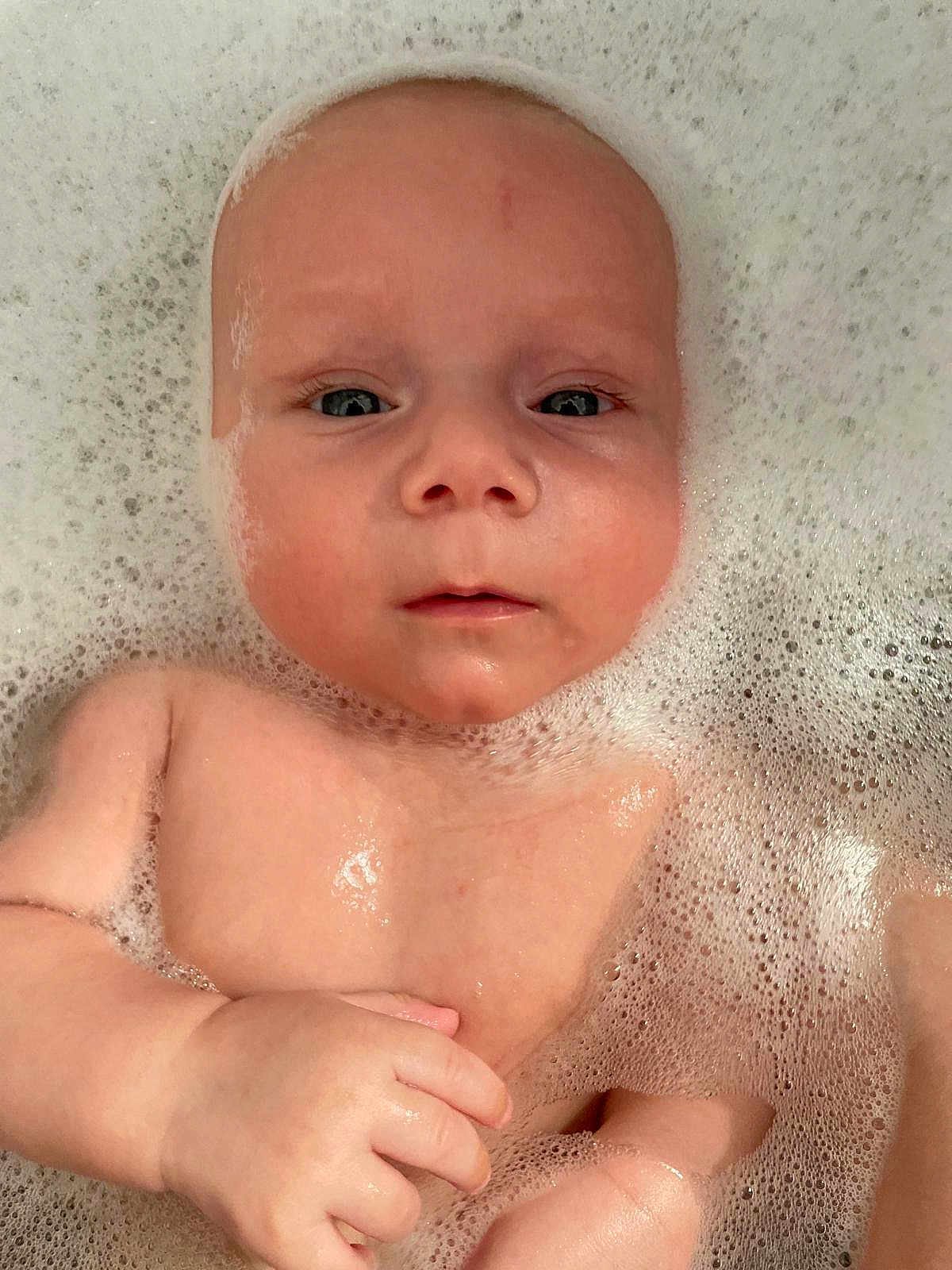 Austin is registered to the contest to win money with this photo: baby, child, bath, bubbles, water, skin, face, hand, infant, cute, relaxing, clean, foam, young, portrait, closeup, wet, expression, background, person