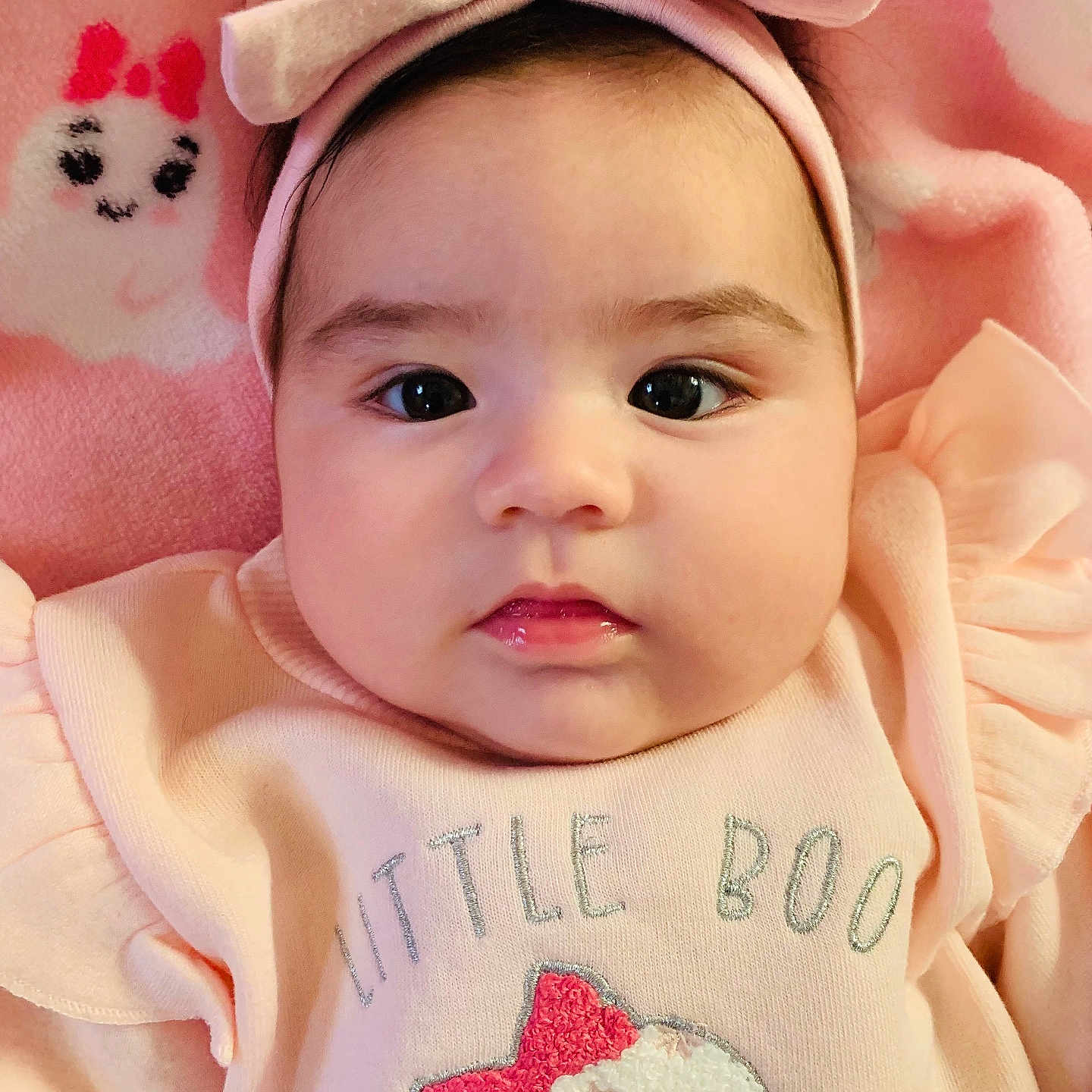 Nathalia joined the competition — help win amazing prizes! adorable, baby, baby_girl, baby_outfit, bow, child, closeup, cute, expressionless, face, headband, indoors, infant, lying_down, pink_background, pink_clothing, portrait, small_person, soft_blanket, text_on_clothing