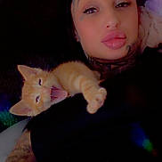 Phillip joined the competition — help win amazing prizes! person, cat, kitten, tattoo, couch, indoor, relaxing, yawning, orange_cat, black_clothing, face, arm, comfort, pet, animal, closeup, portrait, home, resting, cozy