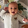 Edison is registered to the contest to win money with this photo: baby, infant, child, smiling, happy, lying_down, portrait, face, eyes, open_mouth, white_onesie, bear_design, play_mat, blanket, plush_toy, nursery, indoor, colorful, soft_lighting, close_up