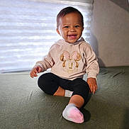 Zoey joined the competition — help win amazing prizes! baby, bed, bedding, black_pants, cartoon, child, cozy, happy, home, hoodie, indoors, infant, minnie_mouse, natural_light, pink, portrait, sitting, smiling, socks, window