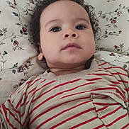 Louis Joseph a rejoint le concours — aidez-le/la à gagner de superbes lots ! baby, blue_eyes, calm_expression, child, close_up, clothing, curly_hair, cute, face, floral_blanket, indoors, infant, lying_down, person, pocket, portrait, skin, soft_light, striped_shirt, young_child