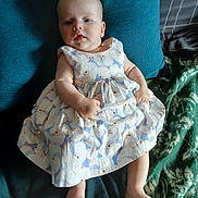 Dana participe au concours pour gagner de l'argent avec cette photo : baby, child, infant, dress, floral_pattern, cushion, blanket, blue, white, person, skin, feet, hands, face, head, indoors, relaxing, seated, cute, portrait