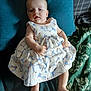 baby, child, infant, dress, floral_pattern, cushion, blanket, blue, white, person, skin, feet, hands, face, head, indoors, relaxing, seated, cute, portrait