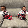 baby, infant, child, couch, sofa, clothing, red_and_black_plaid, socks, smile, thumb_sucking, holiday_outfit, christmas, indoor, furniture, cute, happy, two_children, matching_outfits, sitting, face