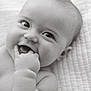 baby, infant, child, smiling, chewing, fingers, close_up, black_and_white, cute, happy, face, skin, lying_down, blanket, portrait, young, expression, innocence, soft, newborn
