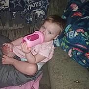 Aaryn is registered to the contest to win money with this photo: baby, blanket, blue_eyes, bottle, brown_hair, child, couch, cozy, drinking, fabric, feet, furniture, hands, home, indoors, infant, pink_clothing, portrait, relaxed, sitting