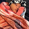 baby, infant, blanket, headband, pink_clothing, face, wrapped, cozy, newborn, soft_texture, portrait, cute, resting, indoors, child, person, warm, sleepy, closeup, fashion_accessory
