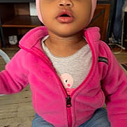 Aalaya joined the competition — help win amazing prizes! bow, casual_wear, child, clothing, curious, expression, face, furniture, headband, home, indoor, jeans, person, pink_jacket, shelf, sitting, television, toddler, wooden_floor, young_child