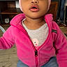 bow, casual_wear, child, clothing, curious, expression, face, furniture, headband, home, indoor, jeans, person, pink_jacket, shelf, sitting, television, toddler, wooden_floor, young_child