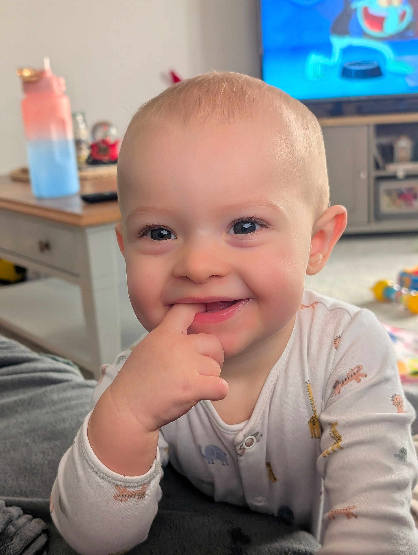 Jaxson joined the competition — help win amazing prizes! baby, child, smiling, face, hand, finger_in_mouth, pajamas, indoor, living_room, television, toy, cute, happy, blond_hair, person, portrait, infant, cozy, furniture, blanket