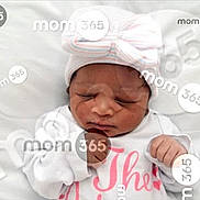 Christina is registered to the contest to win money with this photo: newborn, baby, sleeping, hat, white_clothing, pink_text, cushion, soft, infant, peaceful, portrait, indoors, child, face, hands, closed_eyes, resting, cute, watermark, photography