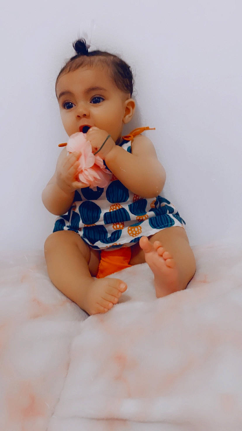 Isabella is registered to the contest to win money with this photo: arm, baby_toddler_clothing, elbow, eye, finger, gesture, hand, happy, head, iris, knee, leg, neck, nose, person, shoulder, skin, sleeve, stomach, textile