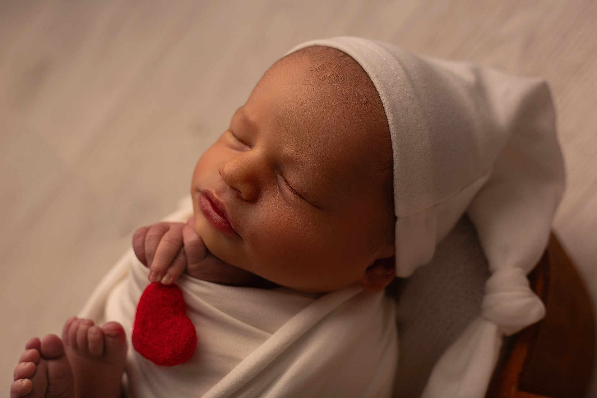 Jules a rejoint le concours — aidez-le/la à gagner de superbes lots ! newborn, baby, infant, sleeping, hat, white_cloth, red_heart, peaceful, closeup, portrait, cute, tiny_hands, tiny_feet, soft_lighting, indoors, wrapped, knotted_hat, skin, face, relaxation