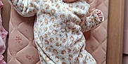 Florence-Louise is registered to the contest to win money with this photo: animal_print, baby, baby_clothes, child, cozy, crib, cute, face, happy, indoor, infant, lying_down, mattress, newborn, onesie, sleepwear, slippers, smiling, soft_texture, wooden_frame