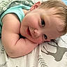 baby, smiling, face, blanket, pillow, child, cute, infant, lying_down, happy, cheeks, blue_eyes, hair, sleeping_area, cozy, soft, indoors, clothing, pattern, resting