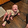 Paisley is registered to the contest to win money with this photo: baby, baby_bottle, cabinet, child, clothing, crawling, face, floor, foot, hand, happy, indoor, kitchen, person, playful, smartphone, smiling, syringe, toddler, wooden_floor