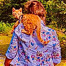animal, back_view, casual_clothing, cat, curious_cat, daytime, floral_jacket, greenery, leash, nature, orange_cat, outdoor, path, person, pet, shoulder, sunlight, trees, walking, yellow_skirt